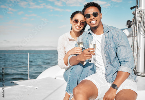Happy couple on yacht with champagne smile and celebrate love with romantic tropical holiday travel on ocean. Dating man and woman on luxury boat on beach water or sea with wine glass for celebration © C Daniels/peopleimages.com