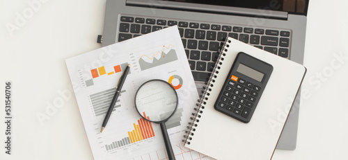 Business graphs, charts, laptop, magnifying glass and calculator on table. Financial development, Banking Account, Statistics