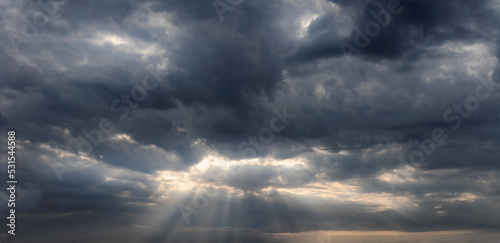 Sky background with sun rays shining through the dark rainy clouds. © Артур Ничипоренко