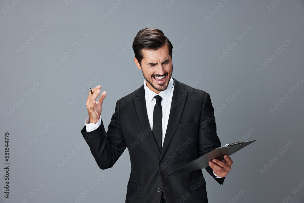Portrait of a business man in a stylish suit smile with teeth hands up handsome face on gray isolated background with tablet in hand. Business concept young businessman startup copy space. Portrait of a business man in a stylish suit smile with teeth hands up handsome face on gray isolated background with tablet in hand. Business concept young businessman startup copy space.