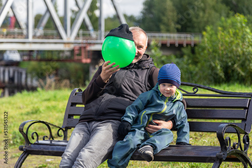 Father and son play with a ball on a bench in autumn. Entertainment with parents. Happy family on the street. © Ekaterina Safronova
