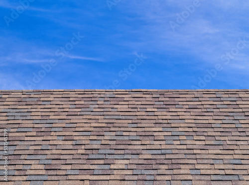 Steep Roofline with Asphalt Shingles under Blue Sky.