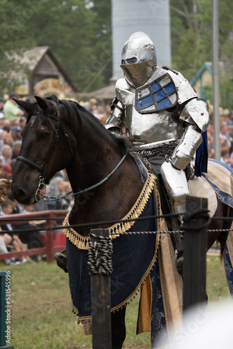 unknown knight in a suit of armor is riding on a horse and ready for battle