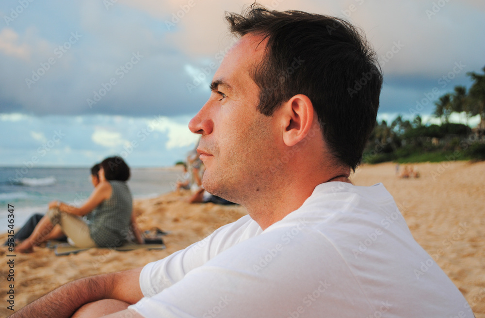 Side view of a young handsome man watching the sunset in Sunset Beach, Oahu, Hawaii Side view of a young handsome man watching the sunset in Sunset Beach, Oahu, Hawaii