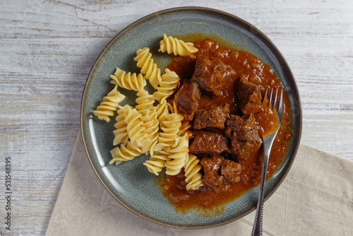 Beef goulash with noodles served on a plate