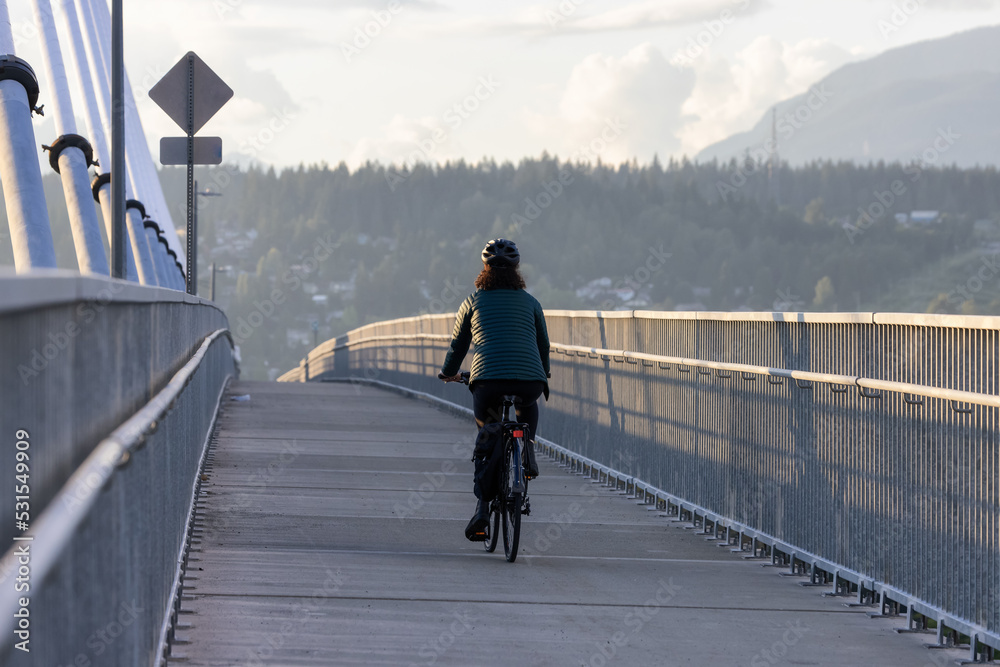 Caucasian Woman riding on a bicycle on a bike lane at Port Mann Bridge