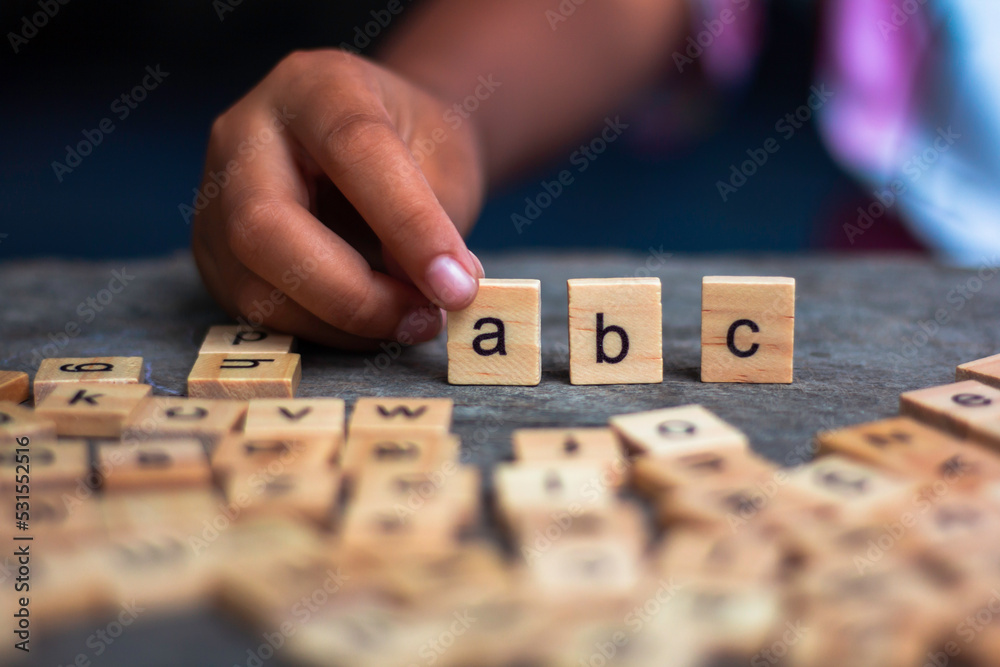 Obraz premium English alphabet made of square wooden tiles with the English alphabet scattered on table. The concept of thinking development, grammar