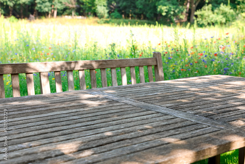 Empty wooden table with bench on sunny day in garden