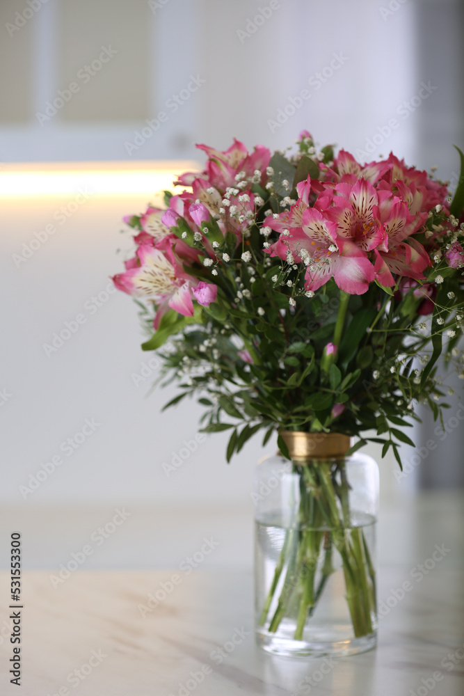 Vase with beautiful alstroemeria flowers on table in kitchen. Interior design