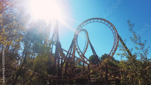 yellow red roller coaster looping in parc Asterix on a sun flare fun summer day. photo