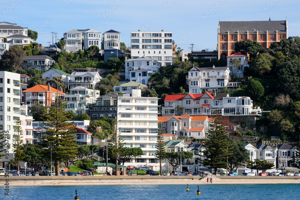 Popular inner city summer spot Oriental Parade beach with residential house, apartments and church, and people enjoying the sun in capital Wellington, New Zealand Aotearoa 