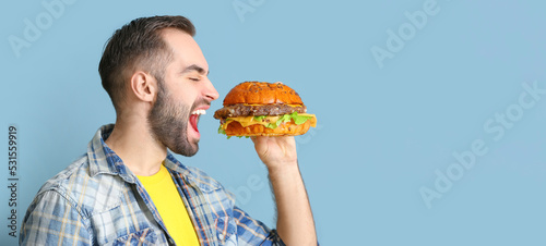Young man eating tasty burg...