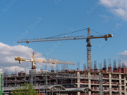 Construction of a multi-storey concrete building. Construction site with cranes and builders. Monolithic concrete. Concrete cast on site