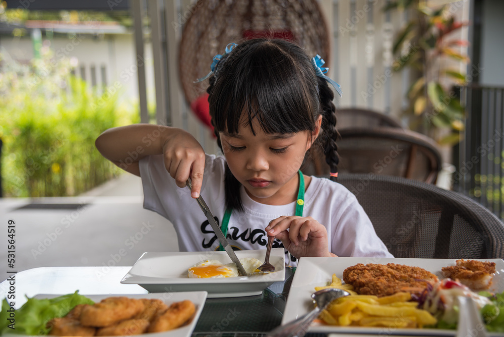 little girl asian eat fried egg on dish at table. little girl asian eat fried egg on dish at table.