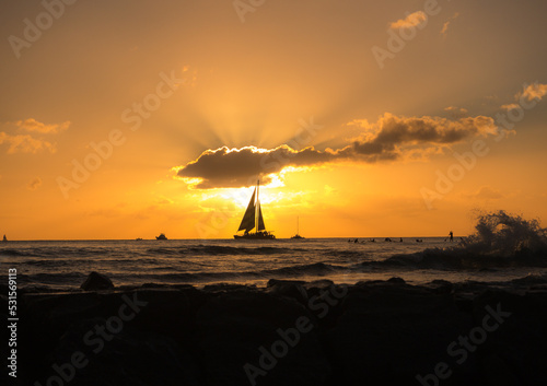 The setting sun in Waikiki was temporarily blocked by a lone cloud just as this sailboat was passing by. A photo was not to be missed!
