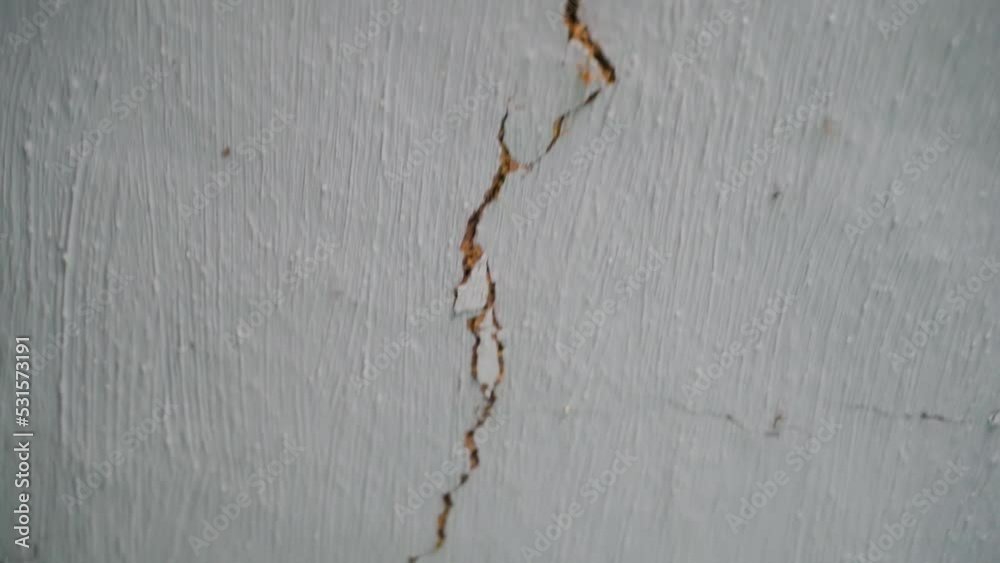 Long crack in the white ceiling of an old rural house close-up. The camera moves along a crack in the clay wall. The rapid destruction of the dwelling and the loss of integrity. after the earthquake
