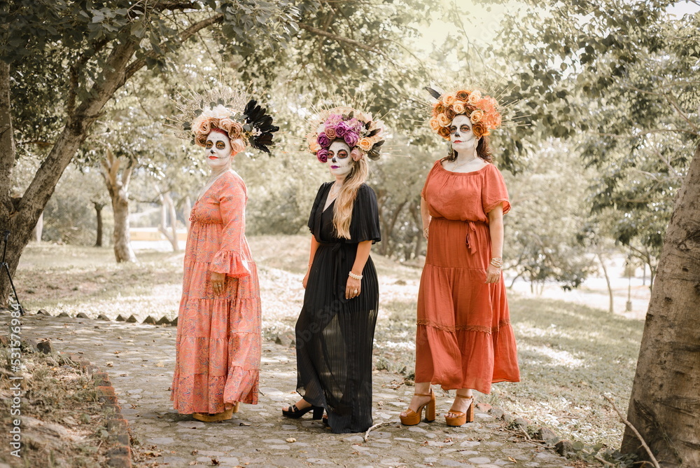 Naklejka premium Group portrait of three women with the makeup of the catrinas.. Makeup for the celebration of Day of the Dead in Mexico. Outdoors portrait.