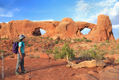 Young girl tourist admiring South and North Windows in Arches National Park, Utah, USA