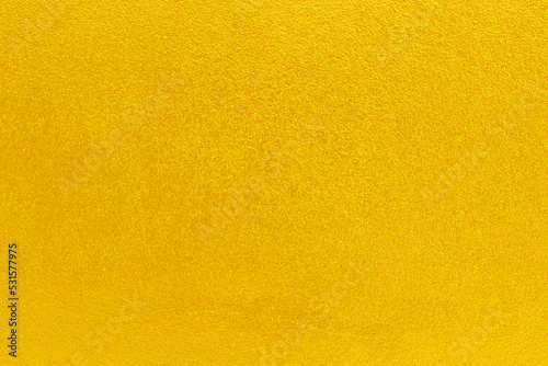 Gold or yellow paint on cement wall texture background.