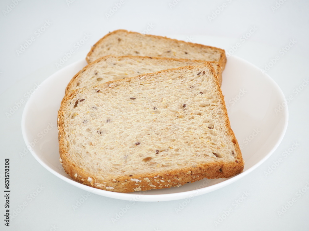 Whole grain bread on a white plate. Closeup photo, blurred.
