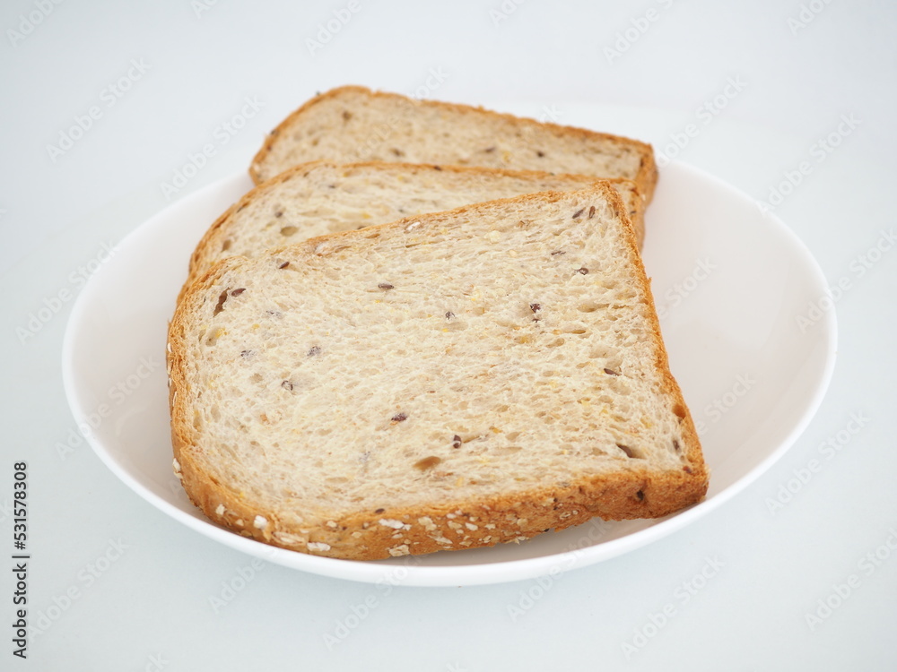 Whole grain bread on a white plate. Closeup photo, blurred. Whole grain bread on a white plate. Closeup photo, blurred.