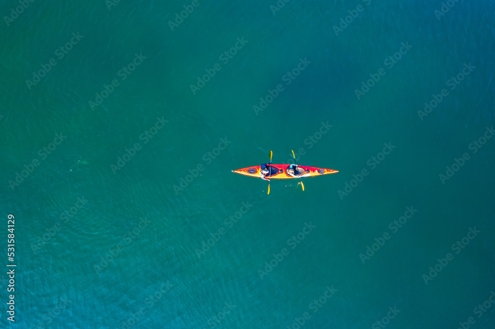 Red kayak boat two rowers on blue turquoise water sea, sunny day. Concept teamwork for business plan, aerial top view