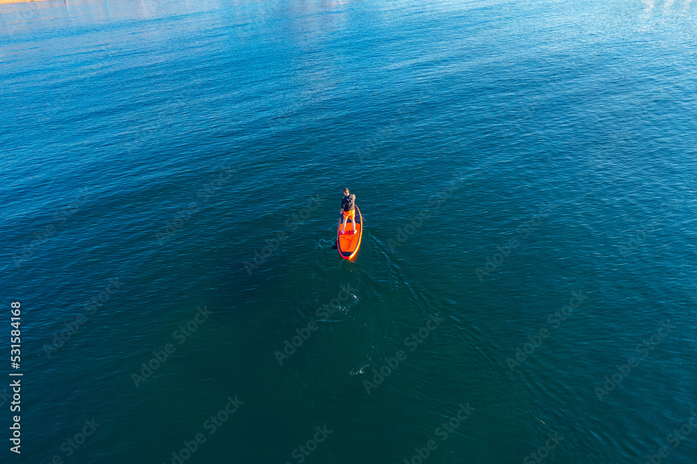Man rowing oar on sup board sea water. Aerial top view sport paddleboard