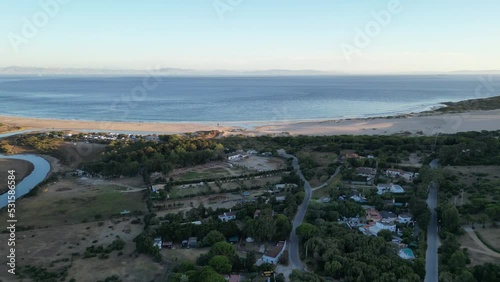 flying over countryside trees towards beach and dune illuminated by sunset. photo