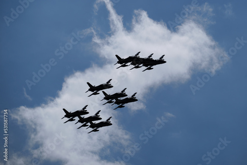Silhouettes of military aircraft on a blue background in flight. A group of nine military aircraft in flight against a blue sky with clouds. photo