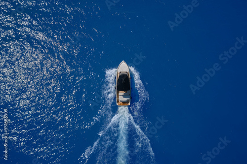 Yacht aerial view. Close range. Pleasure yacht in fast motion on blue transparent water top view.