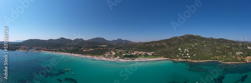 The beaches of Sardinia in the background mountains cumulus clouds top view. Sardinia panorama clear water aerial view. Sardinia famous beaches white sand clear turquoise water aerial view.