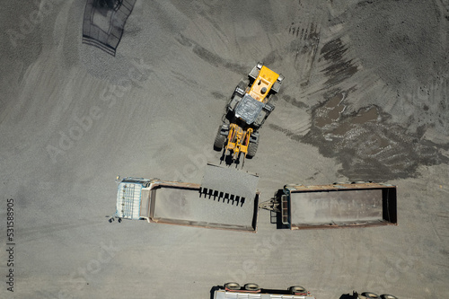 Sand loaders are shoveling rocks into dump trucks.