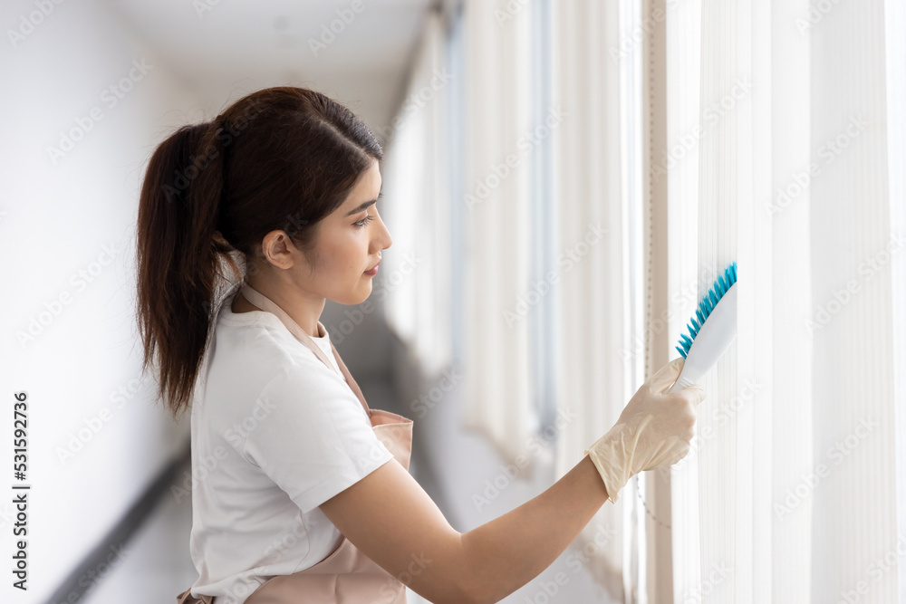 Professional immigrant worker woman cleaning windows blind, domestic helper working hard with housework Professional immigrant worker woman cleaning windows blind, domestic helper working hard with housework