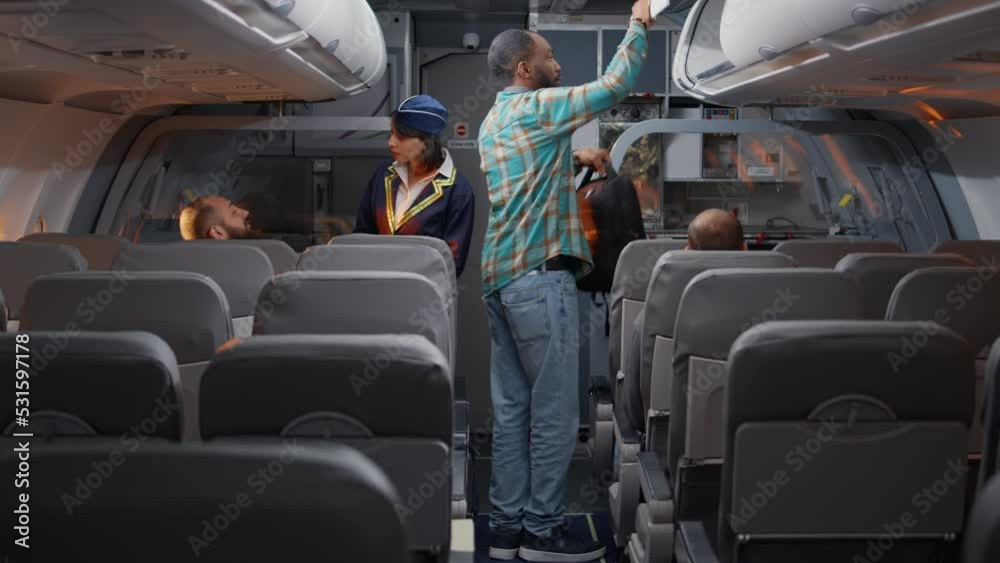 Female flight attendant talking to passengers on airplane, boarding tourists on plane seats. Chatting with people travelling on vacation with international airways in economy class.