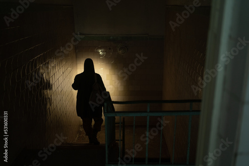 Rear view of a man walking in corridor of the building using flashlight. Nuclear post-apocalypse survivors
