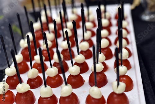 Snacks consisting of tomatoes and cream on them are served quickly on a tray photo