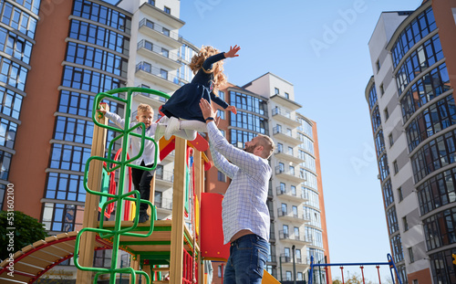 Print op canvas Happy dad catching cheerful daughter, jumping from slide at playground