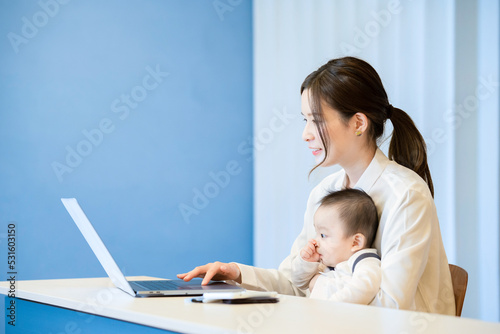 赤ちゃんを抱えてパソコンを操作する女性 