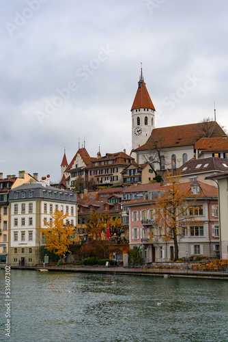 Nice view along Aare lake and Stadtkirche in old town of Thun during autumn , winter cloudy day : Thun , Switzerland : December 2 , 2019