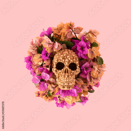 Fototapeta Naklejka Na Ścianę i Meble -  Skull with flowers on pink background. Minmal Halloween or Santa Muerte concept.