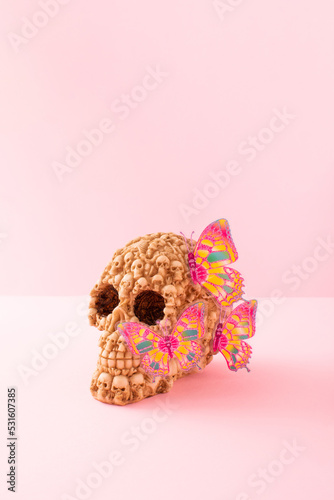 Skull with butterflaies on pink background. Minimal Halloween decoration concept. photo