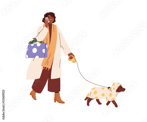 Woman with Christmas shopping bags, speaking on mobile phone, walking with do...
