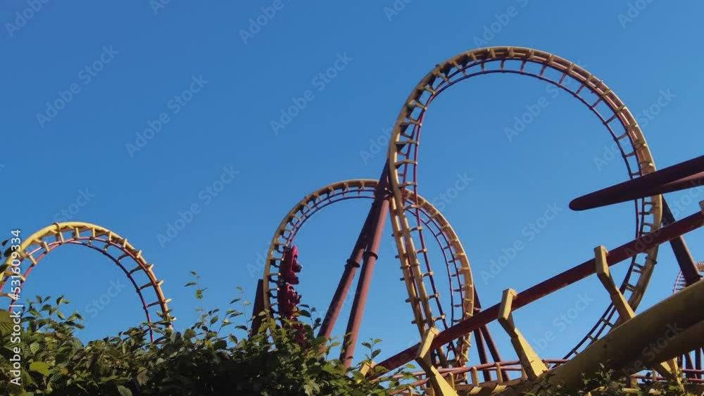 yellow roller coaster in amusement park France takes double loop on a sunny day
