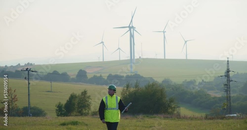 A technician with plans walks through a wind farm in Krystofovy Hamry. Czech republic photo