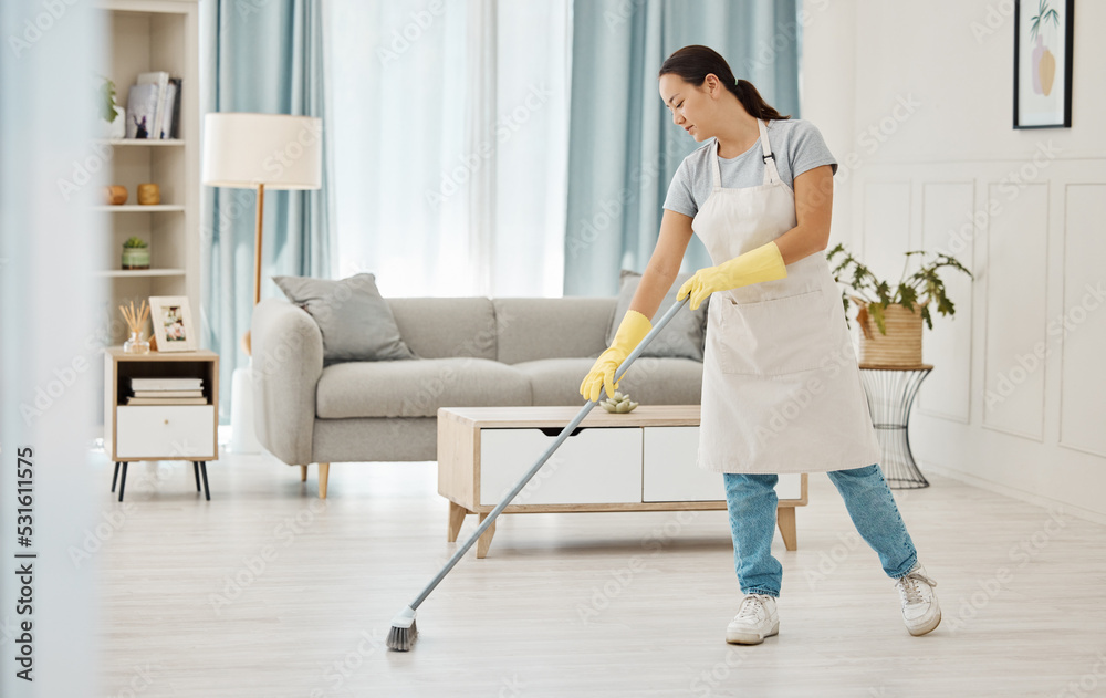 Woman working in a cleaning service mopping the living room floor of a modern home or apartment. Asian cleaner or housewife doing her job or housework to spring clean house for good hygiene lifestyle