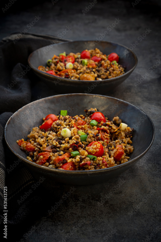 Studio shot of two bowls of bulgur with beluga lentils, tomatoes, peppers, eggplant and scallion Studio shot of two bowls of bulgur with beluga lentils, tomatoes, peppers, eggplant and scallion