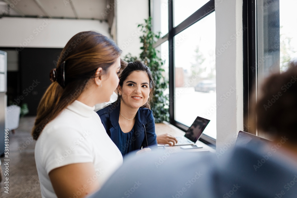 Businesswoman sharing ideas with colleagues in office Businesswoman sharing ideas with colleagues in office