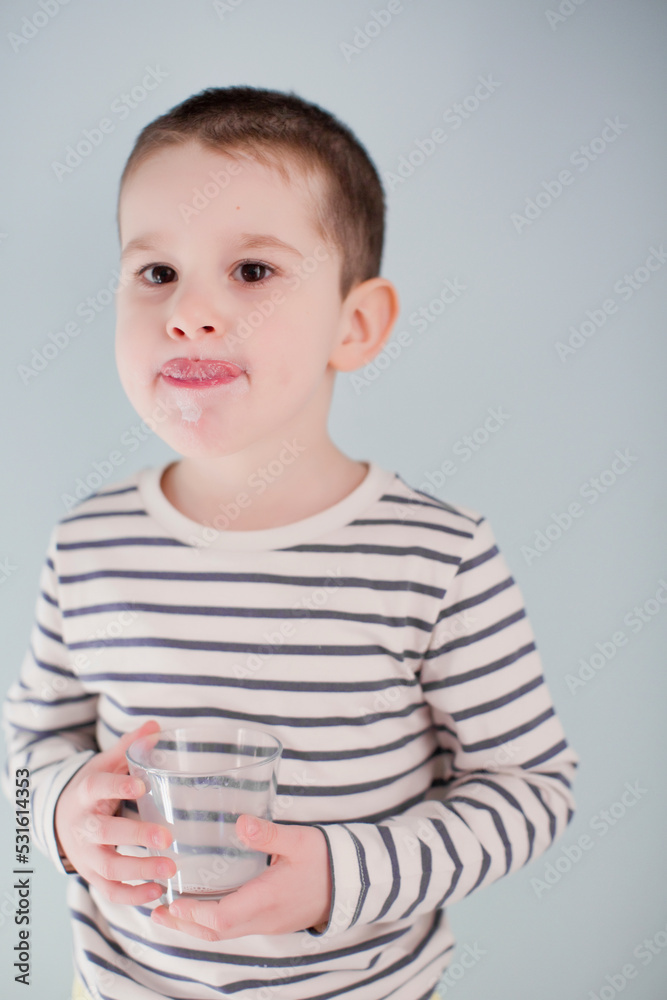 Boy with striped shirt licking lips in front of wall Boy with striped shirt licking lips in front of wall