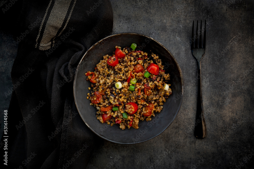 Studio shot of bowl of bulgur with beluga lentils, tomatoes, peppers, eggplant and scallion Studio shot of bowl of bulgur with beluga lentils, tomatoes, peppers, eggplant and scallion