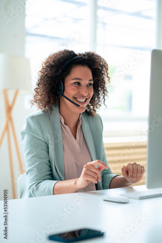 Happy customer service representative discussing through headset at workplace
